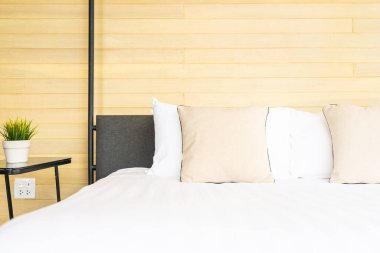 Otel odasındaki yatak odasının iç dekorasyonunda beyaz rahat yastık.