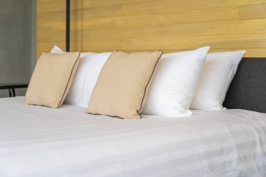 Otel odasındaki yatak odasının iç dekorasyonunda beyaz rahat yastık.