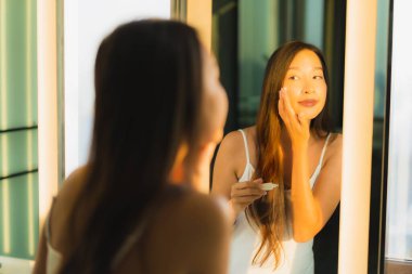 Güzel bir Asyalı kadın portresi. Banyo içinde yüzüne ve yüzüne krem sür.