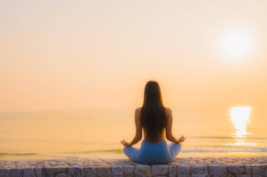 Genç Asyalı kadının portresi sağlık için gün doğumunda deniz kıyısı okyanusunda meditasyon yapıyor.