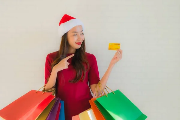 亚洲年轻貌美的女性头戴圣诞礼帽 头戴购物袋 头戴智能手机 头戴信用卡 — 图库照片