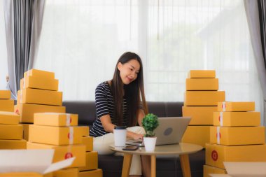 Portre güzel genç Asyalı kadın konteynır paketleme kutusuyla oturma odasında müşteri alışverişi için hazırlanıyor.