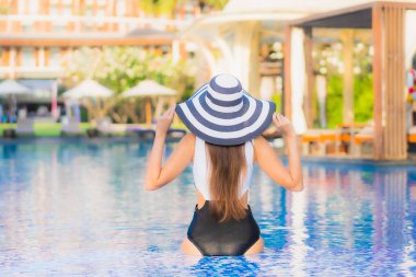 Güzel bir portre genç Asyalı mutlu bir gülümseme tatil beldesi otelinde havuzda rahatça yüzebiliyor.