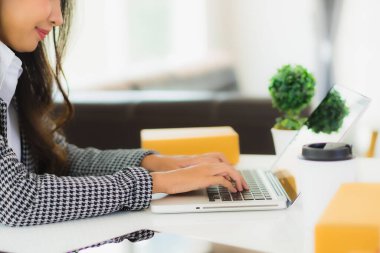 Güzel Asyalı iş kadını portresi evden bilgisayarlı cep telefonuyla karton kutuyla çevrimiçi alışveriş için hazır bekliyor.
