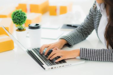 Güzel Asyalı iş kadını portresi evden bilgisayarlı cep telefonuyla karton kutuyla çevrimiçi alışveriş için hazır bekliyor.