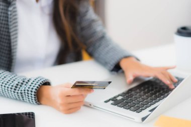 Güzel bir Asyalı kadının portresi online alışveriş malzemesi olarak dizüstü bilgisayarla kredi kartı kullanıyor.