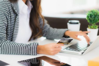 Güzel bir Asyalı kadının portresi online alışveriş malzemesi olarak dizüstü bilgisayarla kredi kartı kullanıyor.