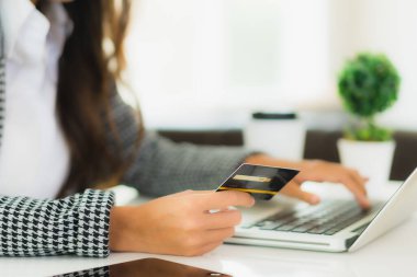 Güzel bir Asyalı kadının portresi online alışveriş malzemesi olarak dizüstü bilgisayarla kredi kartı kullanıyor.