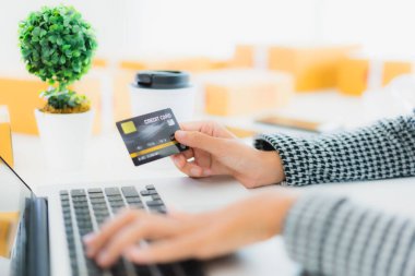Güzel bir Asyalı kadının portresi online alışveriş malzemesi olarak dizüstü bilgisayarla kredi kartı kullanıyor.