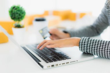 Güzel bir Asyalı kadının portresi online alışveriş malzemesi olarak dizüstü bilgisayarla kredi kartı kullanıyor.