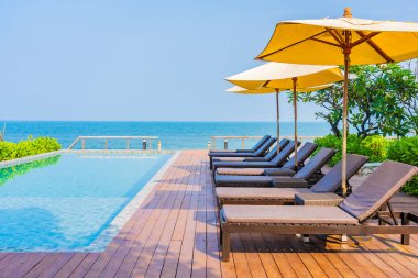 Otel tatil beldesinde açık havuz etrafında güzel boş sandalye şemsiyesi.