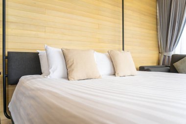 Otel odasındaki yatak odasının iç dekorasyonunda beyaz rahat yastık.