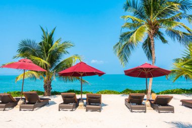 Güzel tropikal deniz okyanusu, şemsiyesi ve sandalyesi ile mavi gökyüzünde hindistan cevizi palmiyesinin etrafında tatil için