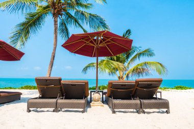 Güzel tropikal deniz okyanusu, şemsiyesi ve sandalyesi ile mavi gökyüzünde hindistan cevizi palmiyesinin etrafında tatil için