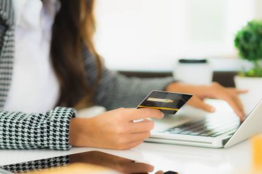 Güzel bir Asyalı kadının portresi online alışveriş malzemesi olarak dizüstü bilgisayarla kredi kartı kullanıyor.