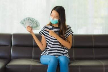 Maskeli güzel Asyalı kadının portresi evde para ya da para gösteriyor.