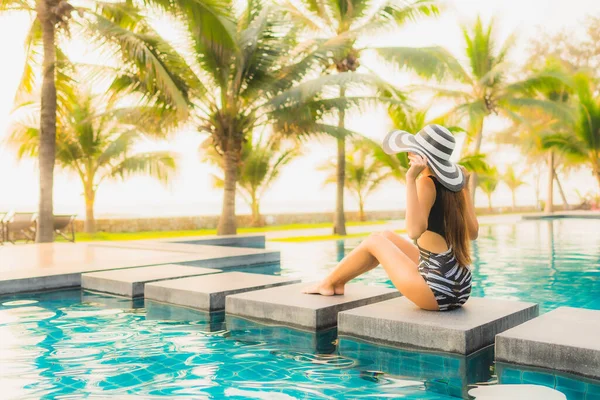 美しい若いアジアの女性は 夕日やレジャー休暇のための日の出でヤシの木とホテルのリゾートで屋外スイミングプールの周りにリラックス — ストック写真