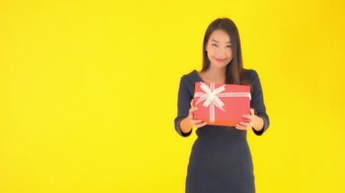 Sarıya izole edilmiş kırmızı hediye kutusu taşıyan güzel Asyalı kadının görüntüleri.