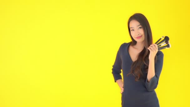 Séquences Belle Asiatique Femme Tenue Maquillage Brosses Isolé Sur Jaune — Video