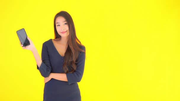 Кадри Красивої Азіатки Показує Смартфон Порожнім Екраном Ізольовані Жовтому — стокове відео