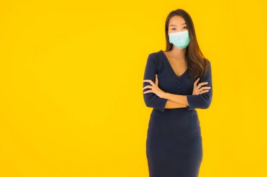 Koronavirüsten korunmak için maske takmış güzel Asyalı bir kadın portresi ve sarı izole edilmiş arka planda 19 numara.