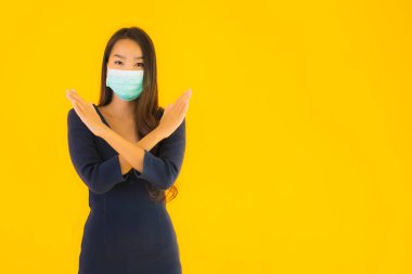 Koronavirüsten korunmak için maske takmış güzel Asyalı bir kadın portresi ve sarı izole edilmiş arka planda 19 numara.