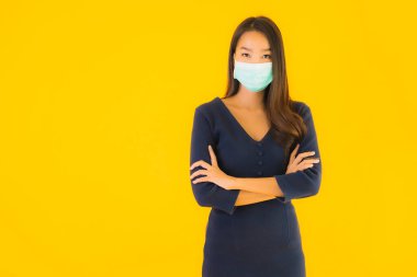 Koronavirüsten korunmak için maske takmış güzel Asyalı bir kadın portresi ve sarı izole edilmiş arka planda 19 numara.