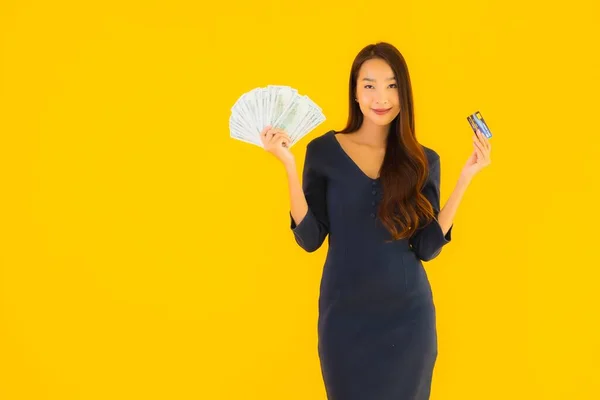 亚洲年轻貌美的女性形象 背景黄色 背景孤立 有现金和信用卡 — 图库照片