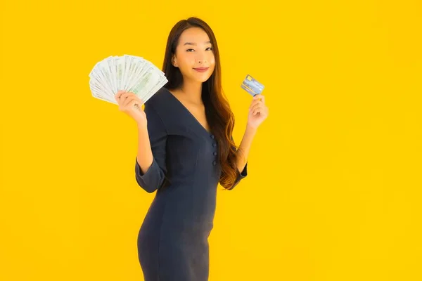 肖像画美しいです若いですアジアの女性とともに現金とクレジットカード上の黄色隔離された背景 — ストック写真