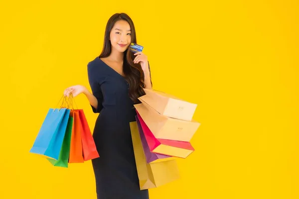 肖像画美しい若いアジアの女性でショッピングバッグクレジットカードとスマートフォン黄色隔離された背景 — ストック写真