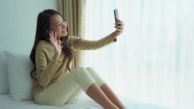 Güzel Asyalı kadının karantina sırasında akıllı telefonuyla video görüşmesi yaptığı görüntüler.