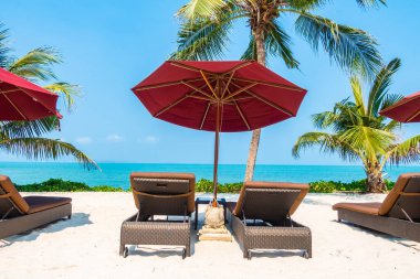 Güzel tropikal deniz okyanusu, şemsiyesi ve sandalyesi ile mavi gökyüzünde hindistan cevizi palmiyesinin etrafında tatil için