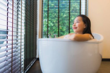Güzel bir Asyalı kadın portresi mutlu bir gülümseme rahatla banyo küvetinde banyo yap.