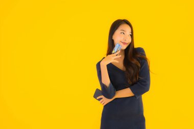 Akıllı cep telefonu, cep telefonu ve kredi kartı sarısı izole bir geçmişi olan güzel Asyalı bir kadın portresi.