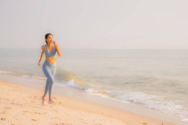 Portre sporu genç Asyalı kadın egzersiz hazırlıyor ya da sağlık için okyanusta koşuyor.