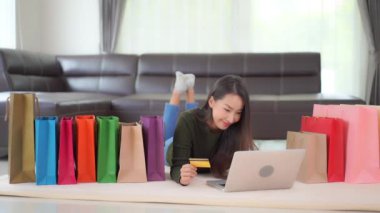 Renkli kağıt torbalarla karantina sırasında evde e-alışveriş yapan Asyalı güzel bir kadının görüntüleri.