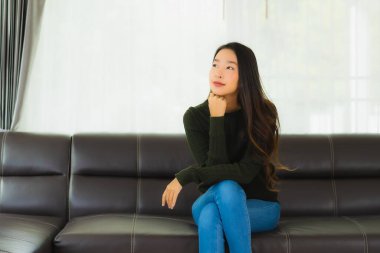Güzel bir portre. Genç Asyalı kadın. Oturma odasındaki kanepede rahatla.