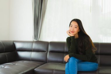 Güzel bir portre. Genç Asyalı kadın. Oturma odasındaki kanepede rahatla.