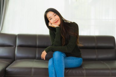 Güzel bir portre. Genç Asyalı kadın. Oturma odasındaki kanepede rahatla.