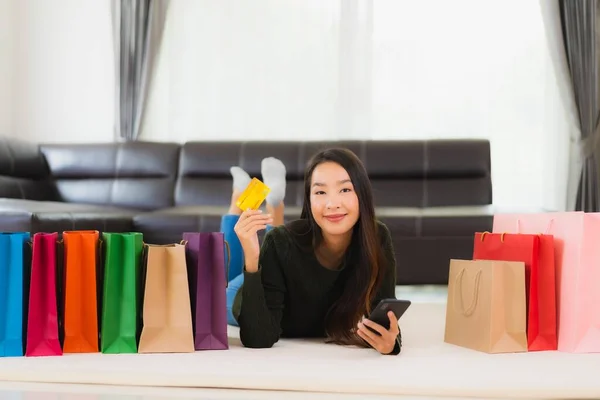 亚洲年轻貌美的女人 带着购物袋和信用卡 带着手机在家网上购物 — 图库照片