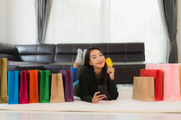自宅でオンラインショッピングのためのショッピングバッグや携帯電話とクレジットカードを持つ肖像画の美しい若いアジアの女性 — ストック写真