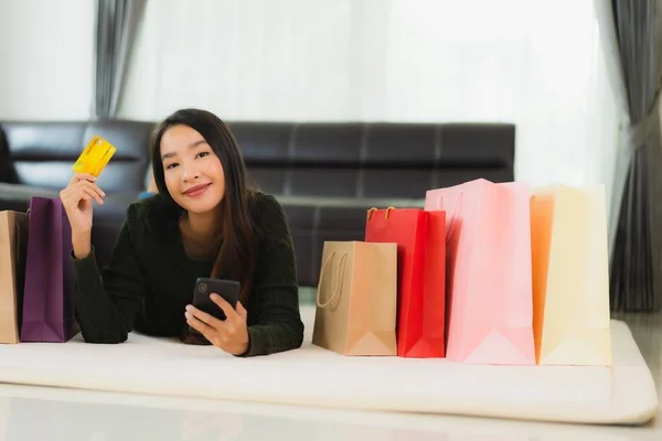 亚洲年轻貌美的女人 带着购物袋和信用卡 带着手机在家网上购物 — 图库照片