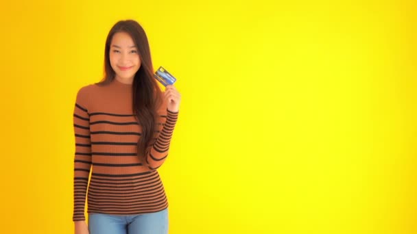 Metraje Hermosa Mujer Asiática Sosteniendo Tarjeta Crédito Aislado Amarillo — Vídeos de Stock