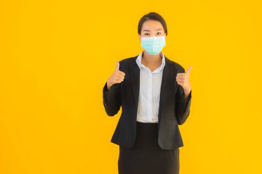 Güzel genç iş kadını portresi Korunmak için maske takıyor 19 koronavirüs sarı izole arka planda