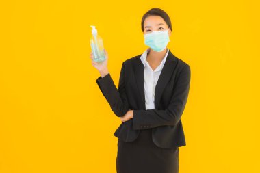 Güzel bir iş kadını portresi. Maske takıyor. Korunmak için alkol jeli kullanıyor.
