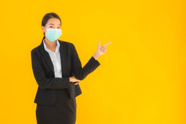 Güzel genç iş kadını portresi Korunmak için maske takıyor 19 koronavirüs sarı izole arka planda
