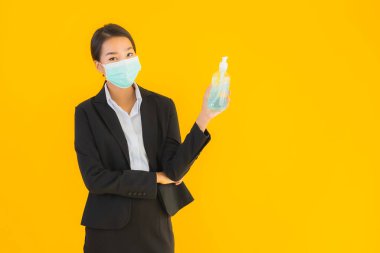 Güzel bir iş kadını portresi. Maske takıyor. Korunmak için alkol jeli kullanıyor.