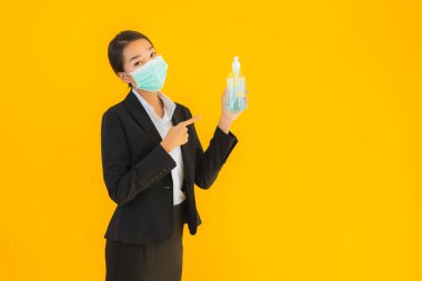 Güzel bir iş kadını portresi. Maske takıyor. Korunmak için alkol jeli kullanıyor.