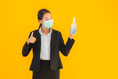 Güzel bir iş kadını portresi. Maske takıyor. Korunmak için alkol jeli kullanıyor.