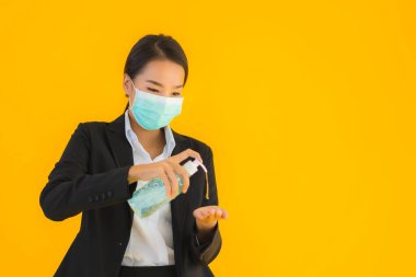 Güzel bir iş kadını portresi. Maske takıyor. Korunmak için alkol jeli kullanıyor.